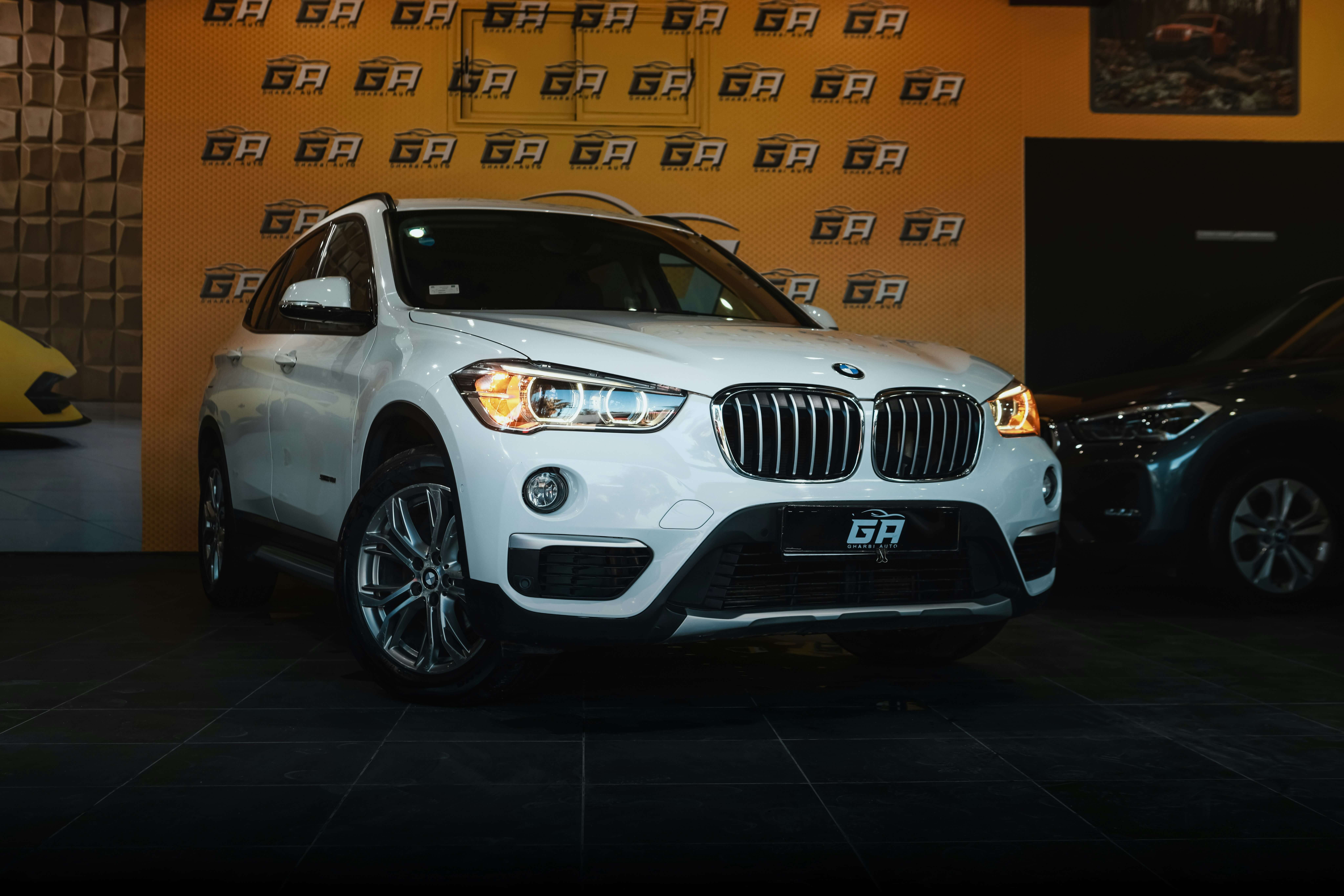 Silver 2025 BMW X1 parked on city street, showcasing its bold lines, signature kidney grille, and LED headlights.