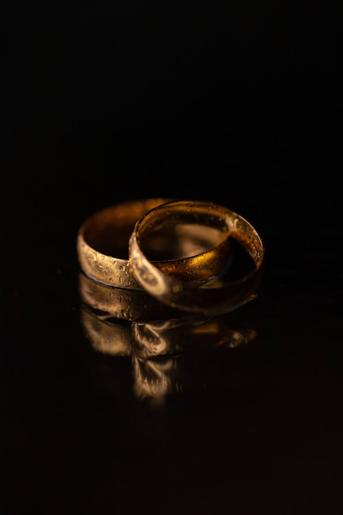 Close-up of polished 24 K gold rings stamped “999.9” arranged on a dark surface.